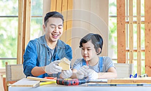 Asian professional male carpenter woodworker engineer dad in jeans outfit with safety gloves holding small home model teaching