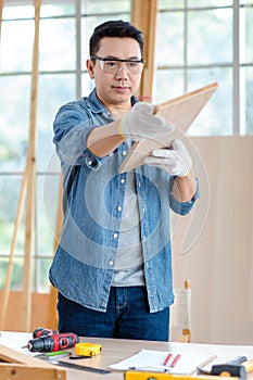 Asian professional male carpenter woodworker engineer in jeans outfit with safety gloves and goggles using measuring ruler pencil