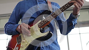 Asian professional musician playing electric guitar in music practice room.