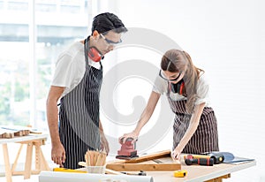 Asian professional skilled male carpenter worker staff in apron with earphones and safety goggles standing holding using polishing