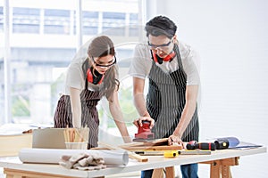 Asian professional skilled male carpenter worker staff in apron with earphones and safety goggles standing holding using polishing