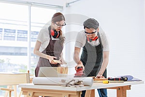 Asian professional skilled male carpenter worker staff in apron with earphones and safety goggles standing holding using polishing