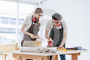 Asian professional skilled male carpenter worker staff in apron with earphones and safety goggles standing holding using polishing