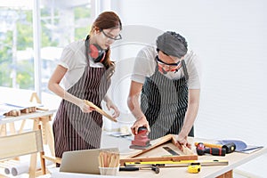 Asian professional skilled male carpenter worker staff in apron with earphones and safety goggles standing holding using polishing