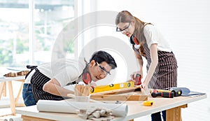 Asian professional skilled male carpenter worker staff in apron with earphones and safety goggles standing using water level gauge