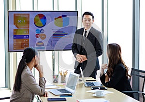 Asian professional successful businessman in formal suit standing showing presenting explaining report investment graph chart data
