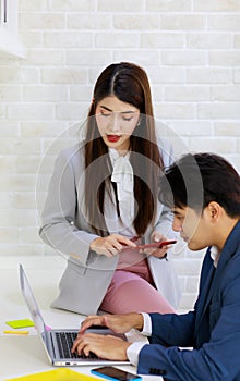 Asian professional successful businesswoman employee sitting working with laptop notebook computer on workstation desk while male