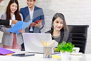 Asian professional successful businesswoman employee sitting working with laptop notebook computer on workstation desk while male