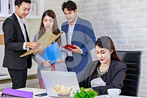 Asian professional successful businesswoman employee sitting working with laptop notebook computer on workstation desk while male