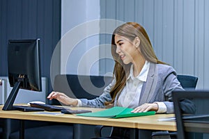 Asian professional successful female businesswoman employee secretary in formal business suit sitting working on computer screen