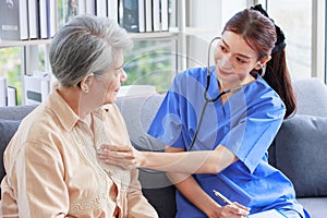 Asian professional successful female internship nurse in blue uniform sitting on sofa couch smiling using stethoscope listening to