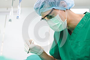 Asian professional surgeon holding a scalpel with glasses and wear gloves and a mask