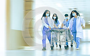 Asian professional teamwork doctors, nurses in surgical gown and white coat uniform running with hurry, taking emergency patient