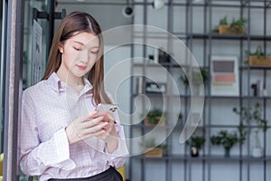 Asian professional working woman uses smartphone to chat with someone in digitalization and work from home concept