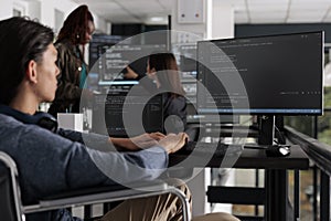 Asian programmer with physical disability typing html code on computer