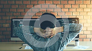 Asian programmers man are relaxing and looking at the code on the computer screen in the office