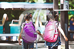 Asian pupil kids with backpack holding hand and going to school