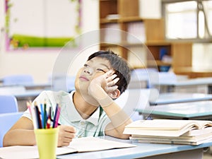 Asian pupil thinking in classroom