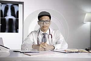 Asian qualified physician in health care facility paying attention and listening to patient for diagnosis and treatment plan