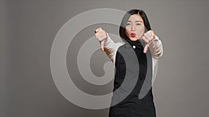 Asian restaurant hostess showing thumbs down and dislike sign