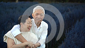 Asian retired senior couple celebrating winter in beautiful blue magical flower field