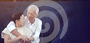 Asian retired senior couple celebrating winter in beautiful blue magical flower field