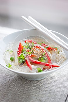 Asian rice noodles with vegetables and sesame in a bowl on a linen textile background