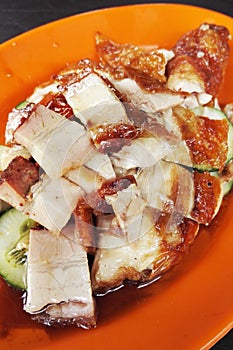 Asian roast chicken and pork belly on orange plate