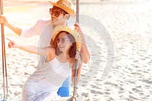 Asian romantic couple is sitting on sea beach on rope swing relax and happiness for holiday.