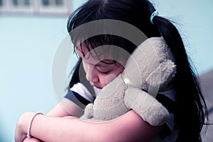 Asian sad child girl hugging teddy bear with love