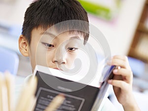 Asian school boy reading a book