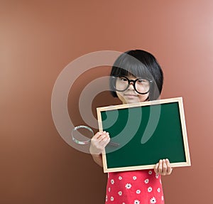 Asian school kid hold a chalkboard and magnifying glass