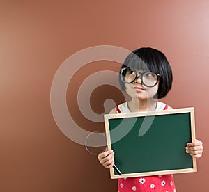 Asian school kid hold a chalkboard and magnifying glass