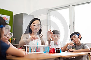 Asian School Kids doing chemicals with Female Teacher