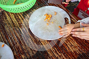 Asian school kids learn to cut vegetable in cooking class closeup