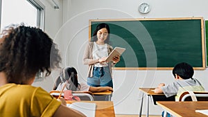 Asian school teacher using digital device with children in classroom at school, technology, learning, development