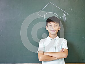 Asian schoolboy standing under a chalk-drawn doctoral cap photo