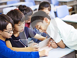 Asian schoolchildren using digital tablet together