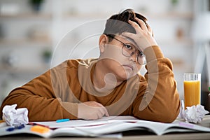 Asian schooler dreaming about something while doing homework