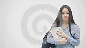 An asian schoolgirl appearing on a white background with a backpack slung over her shoulder, holding a stack of books