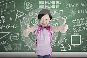 Asian schoolgirl shows thumbs up in classroom