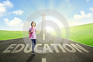 Asian schoolgirl standing above education word