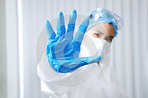 Asian Scientific experimenter Woman Wearing blue protective rubber gloves and showing stop hand sign for Covid-19 virus pathogens