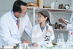 Asian scientist kid student and Indian teacher with plant at biology class in school laboratory, learning, teaching child girl to