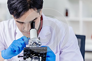 Asian scientist researcher looking at microscope working in medical lab