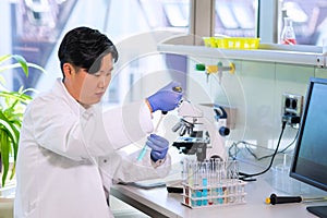 Asian scientist working in lab. Doctor making microbiology research. Laboratory tools: microscope, test tubes, equipment