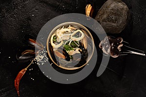 Asian seafood soup with mussels, octopus, squid rings, noodles, sesame seeds