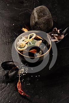 Asian seafood soup with mussels, octopus, squid rings, noodles, sesame seeds