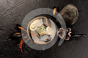 Asian seafood soup with mussels, octopus, squid rings, noodles, sesame seeds