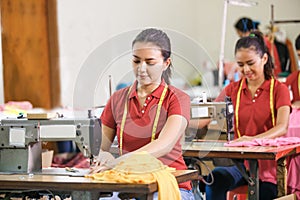 asian seamstress in garment factory sewing with industrial sewin